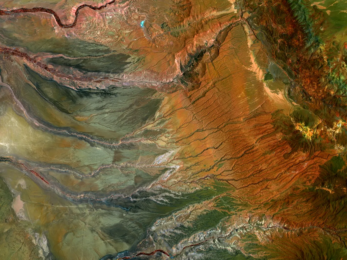 Aerial image of eroded, multicolored terrain cut by drainage channels.